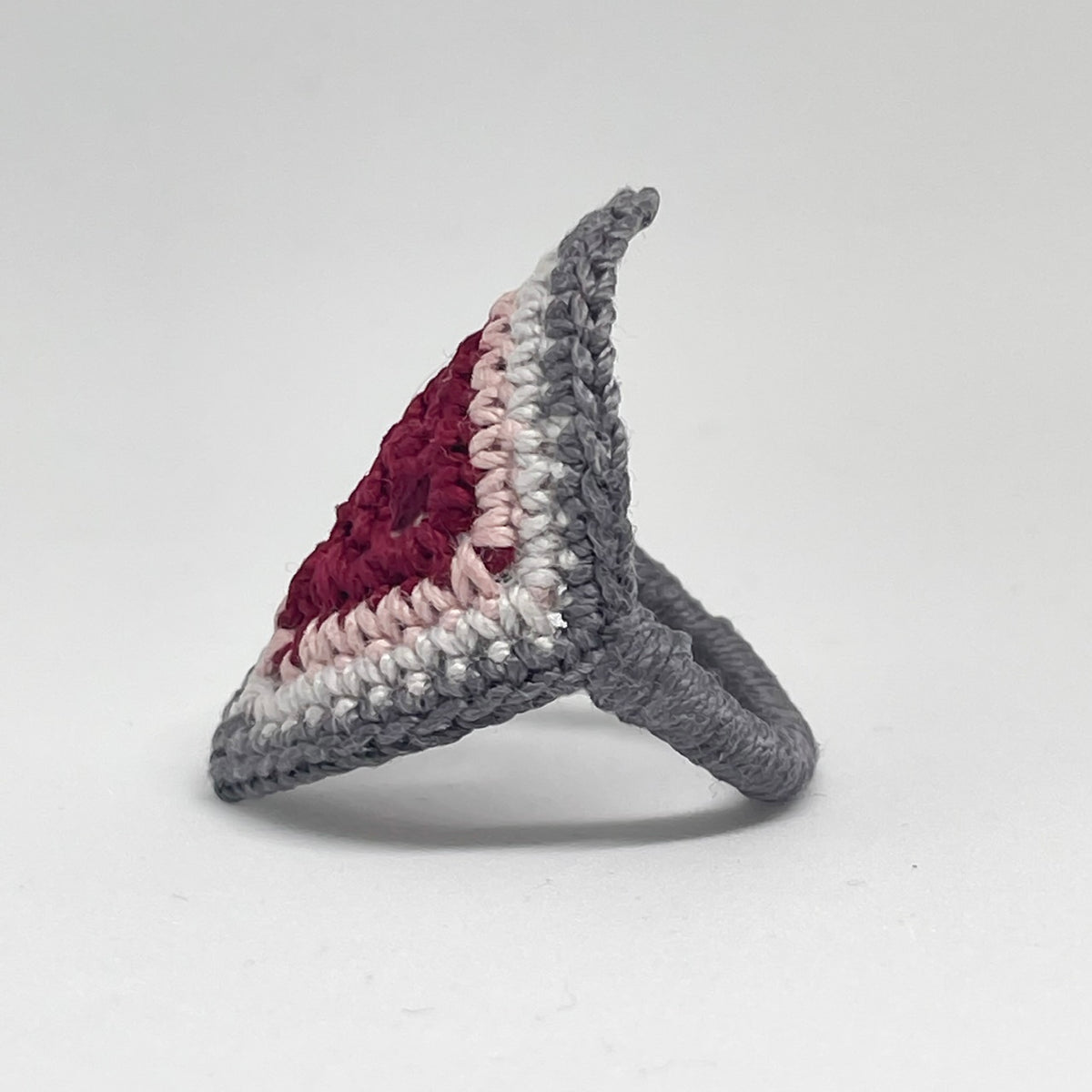 Side view of the TRAMA crochet ring with a burgundy centre, pink, light gray and gray borders, showing the gray crochet band.